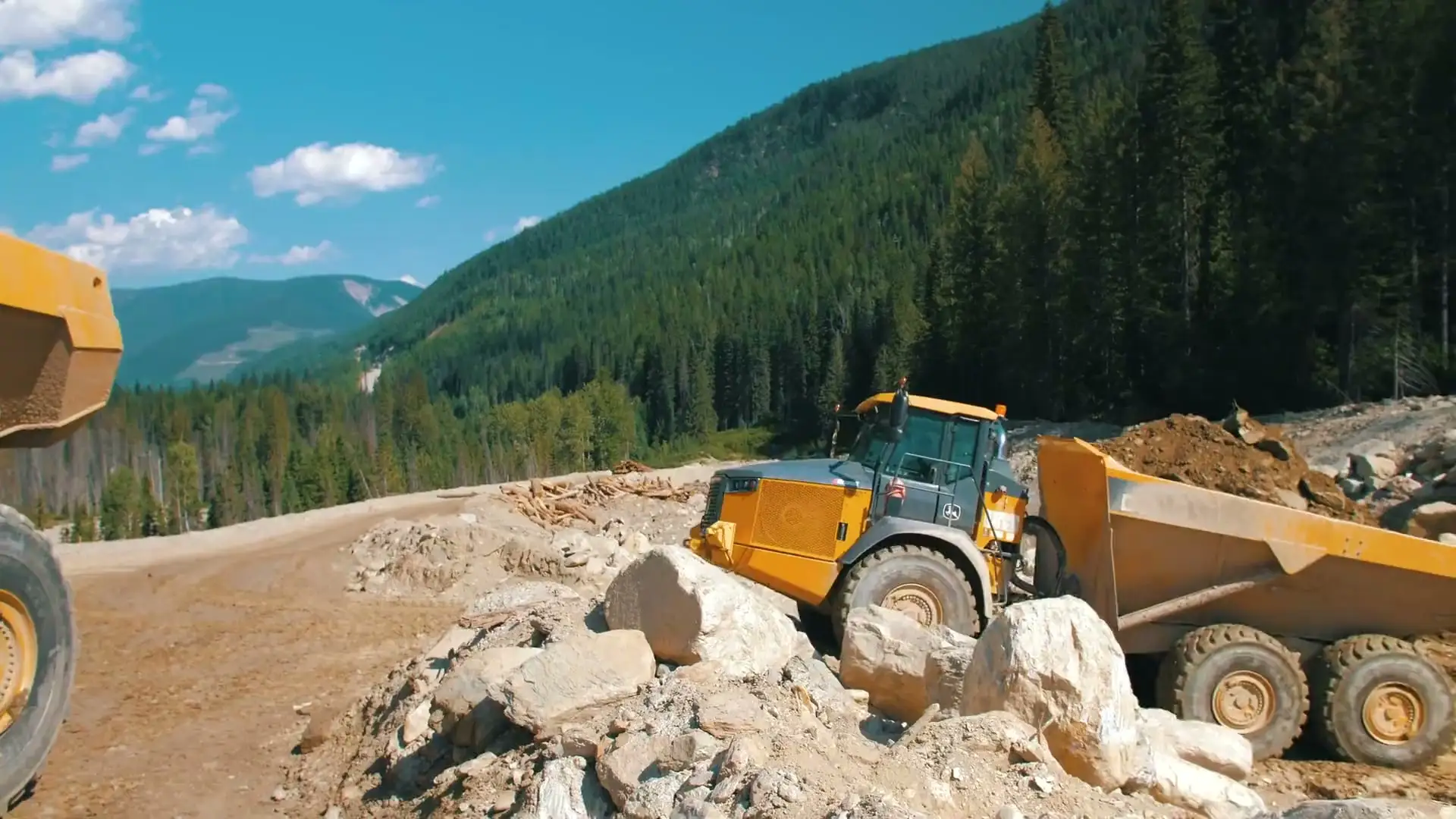 MacKay rock trucks hauling in a forested mountain valley