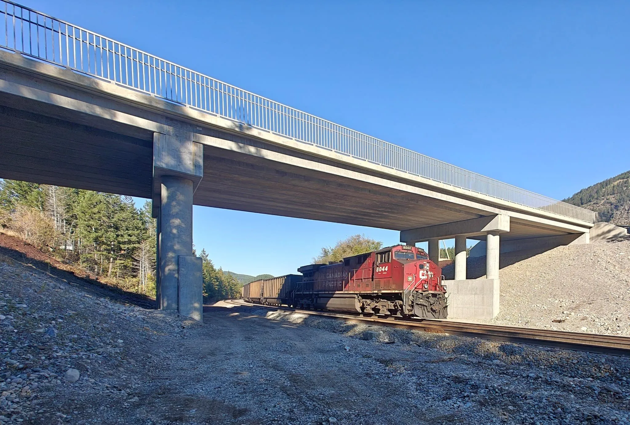 Freight train passing beneath the completed Elko Overhead bridge