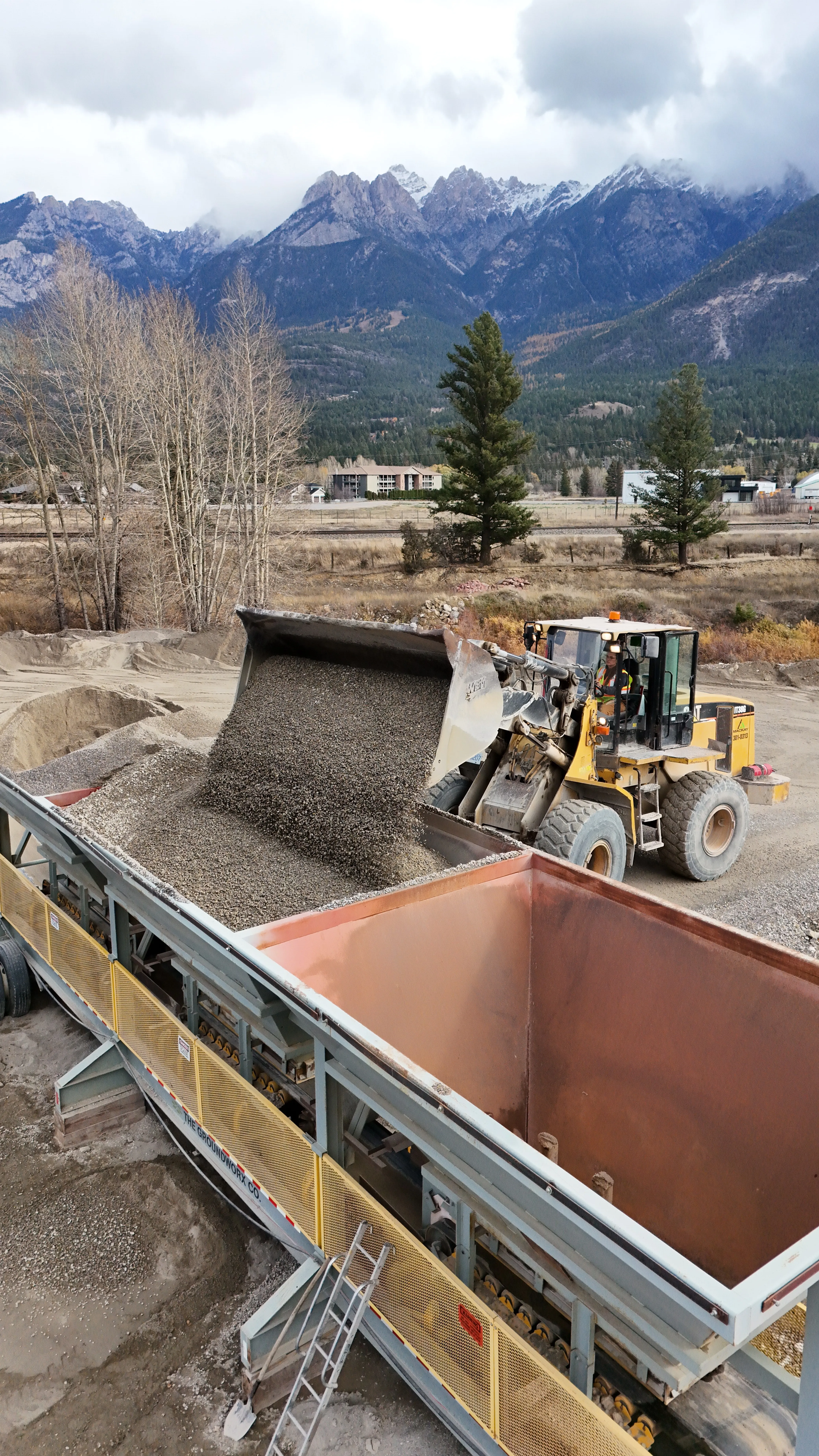 Wheel loader feeding a crusher beneath snow-capped peaks
