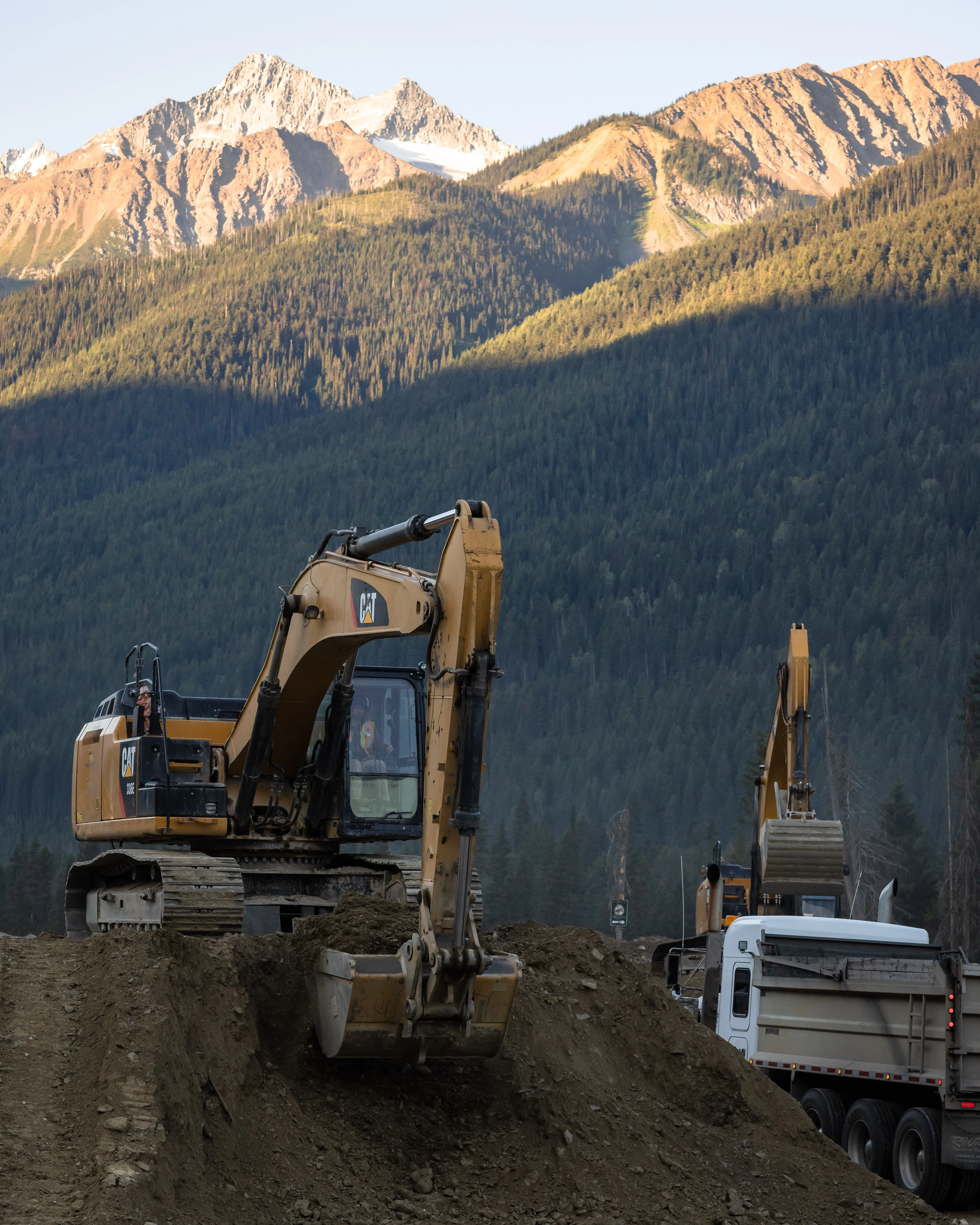 Excavator loading a dump truck with material at golden hour
