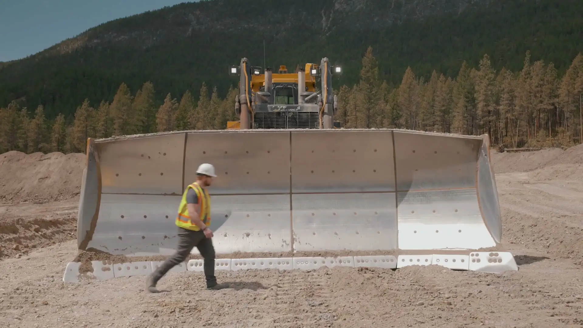 Crew member walking the blade of a MacKay dozer on site