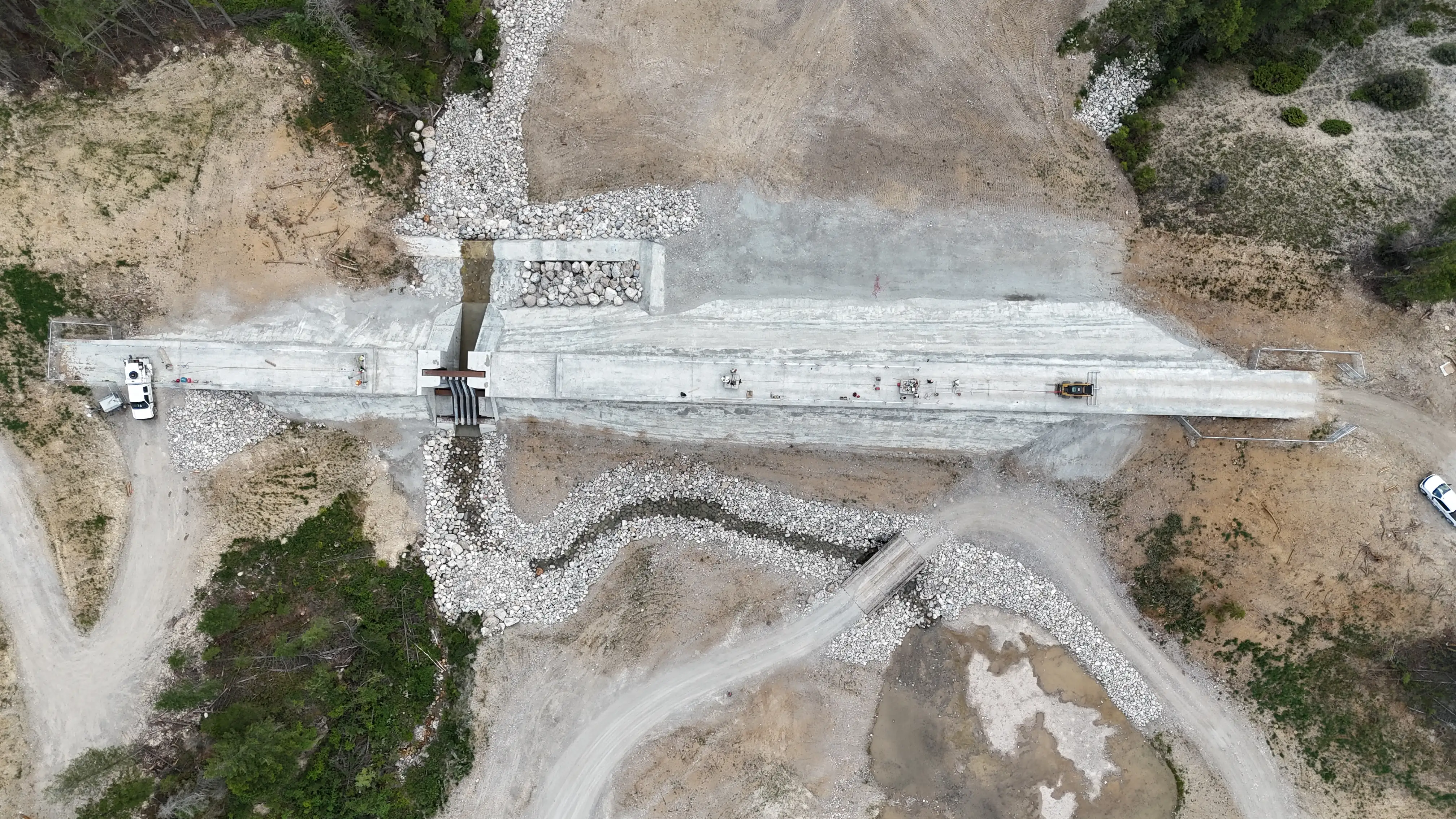 Top-down aerial of the completed debris-flow dam and spillway