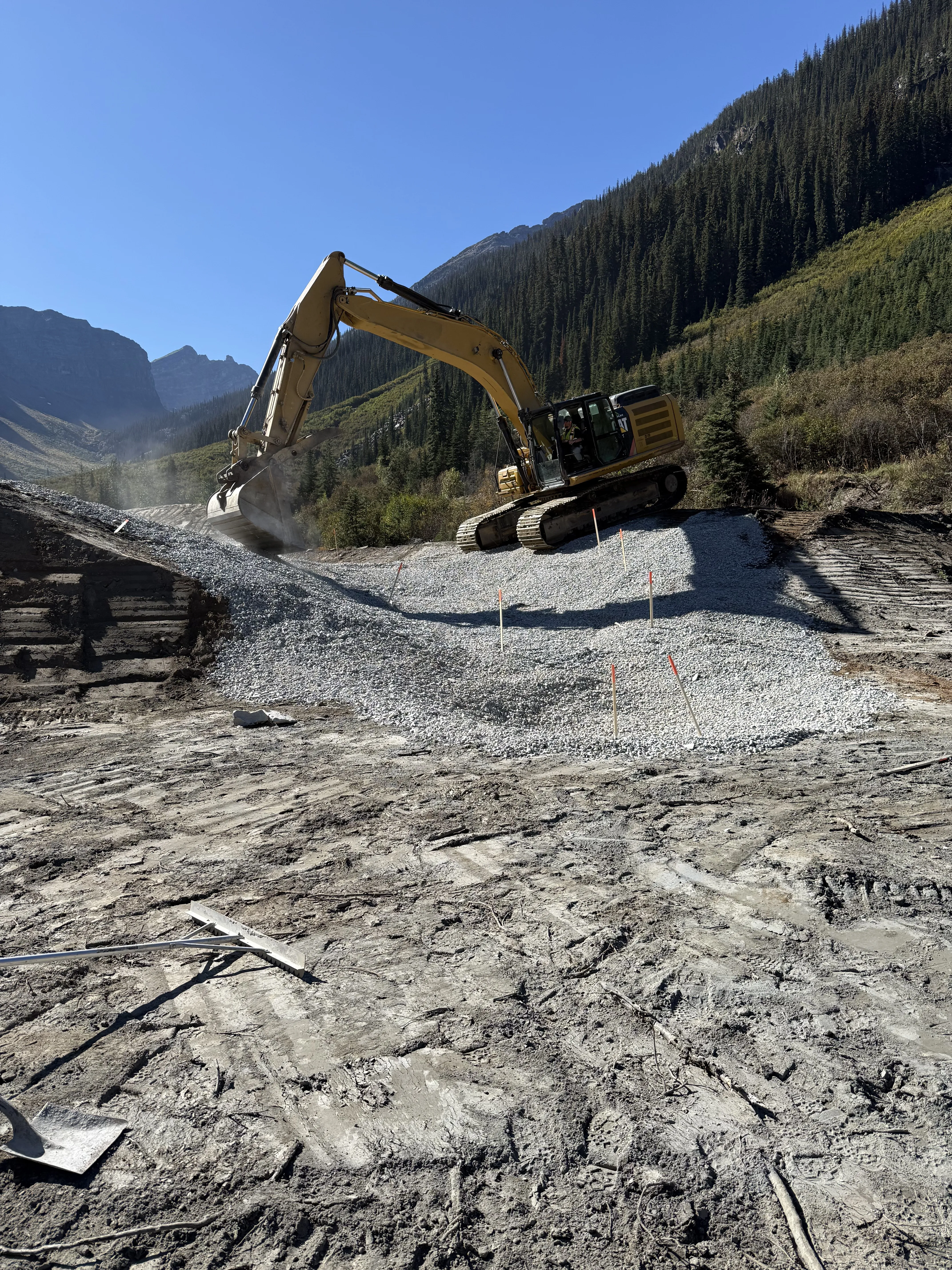 Excavator placing riprap during mine reclamation in an alpine valley